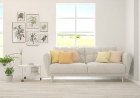 White,Living,Room,With,Sofa,And,Summer,Landscape,In,Window.